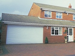 Double roller shutter door installed infront of flat brick driveway