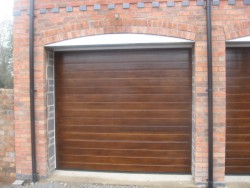 Timber-effect sectional garage door installed on brickwork