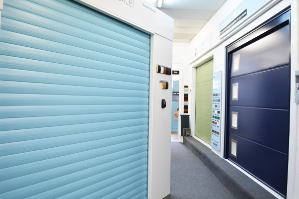 Blue roller door and blue sectional door in The Garage Door Centre showroom