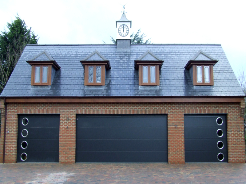 Three anthracite Carteck solid ribbed steel sectional garage doors. Two with porthole windows